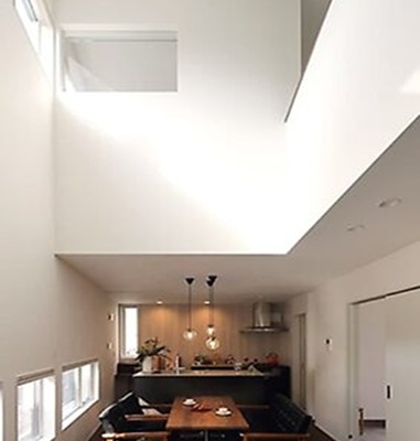 2世帯住宅の下の階のダイニングキッチン。床面を掘り下げて天井高を確保し、高窓（ハイサイドライト）から光を取り込んでいる